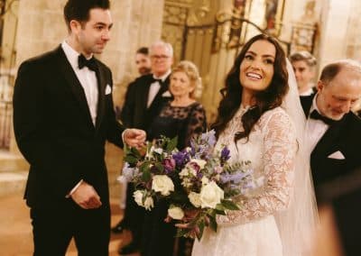Emotional groom looks at bride holding flowers in Pessan Church ceremony