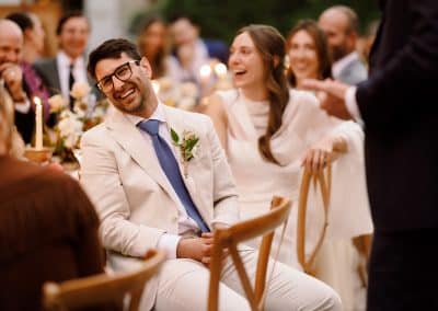 Bride and groom laugh while listening to speeches during the wedding meal