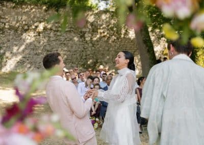 Bride and groom holding hands and laughing at the end of their wedding ceremony at Chateau de Lartigolle