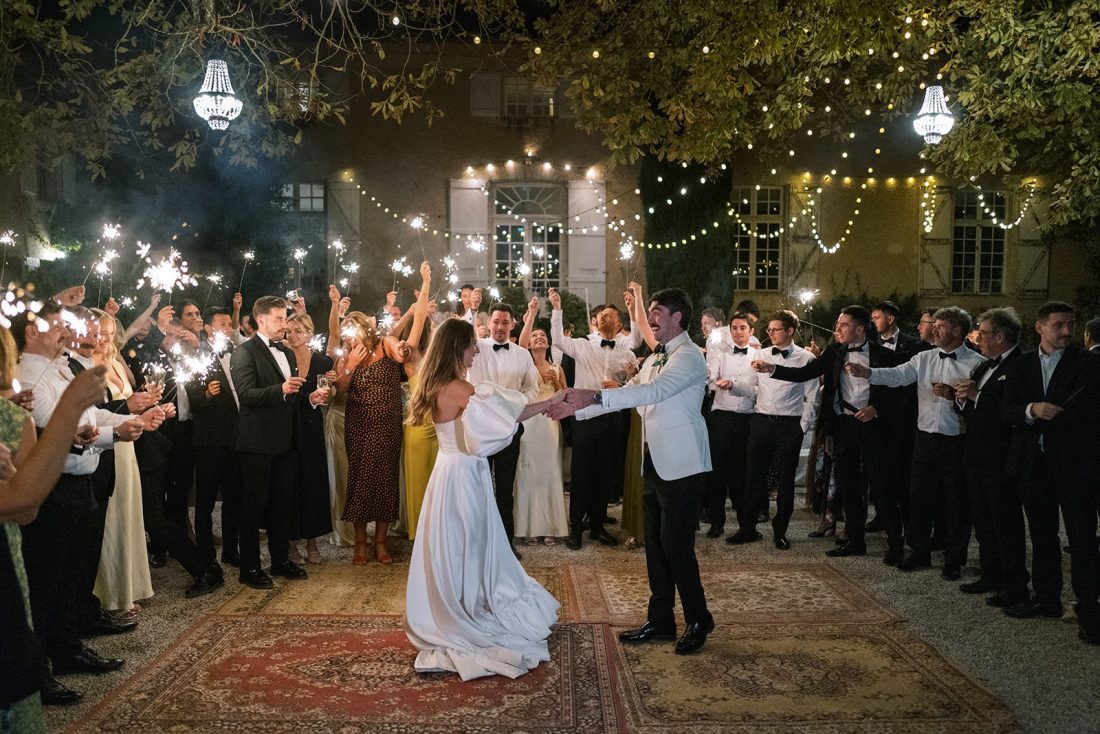 A couple celebrate with their first dance surrounded by sparkler waving friends and family in the courtyard at Chateau de Lartigolle