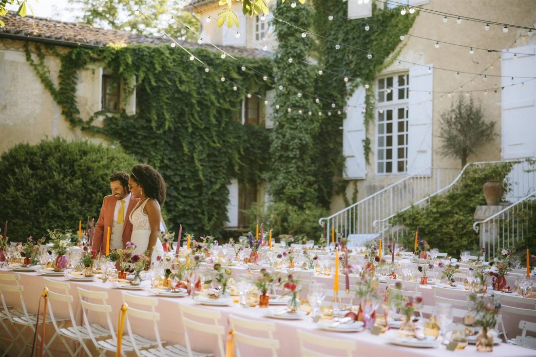 Bride and Groom inspect their table setting ahead of the meal in the coutrtyard at Chateau de Lartigolle