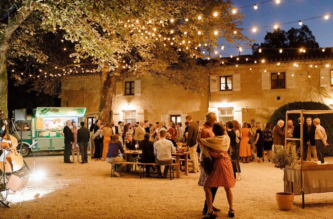 Guests enjoy a evening fête style party in the courtyard of the chateau de Lartigolle
