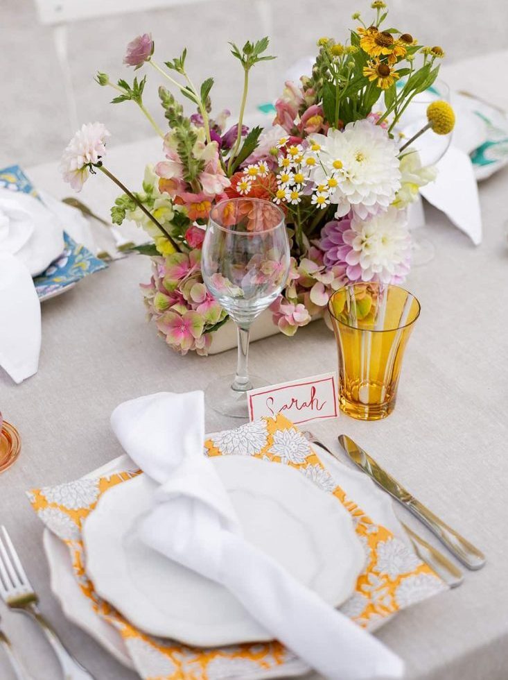 Hand-sourced coloured napkins mix with coloured glassware and bright pops of colour from the florals.